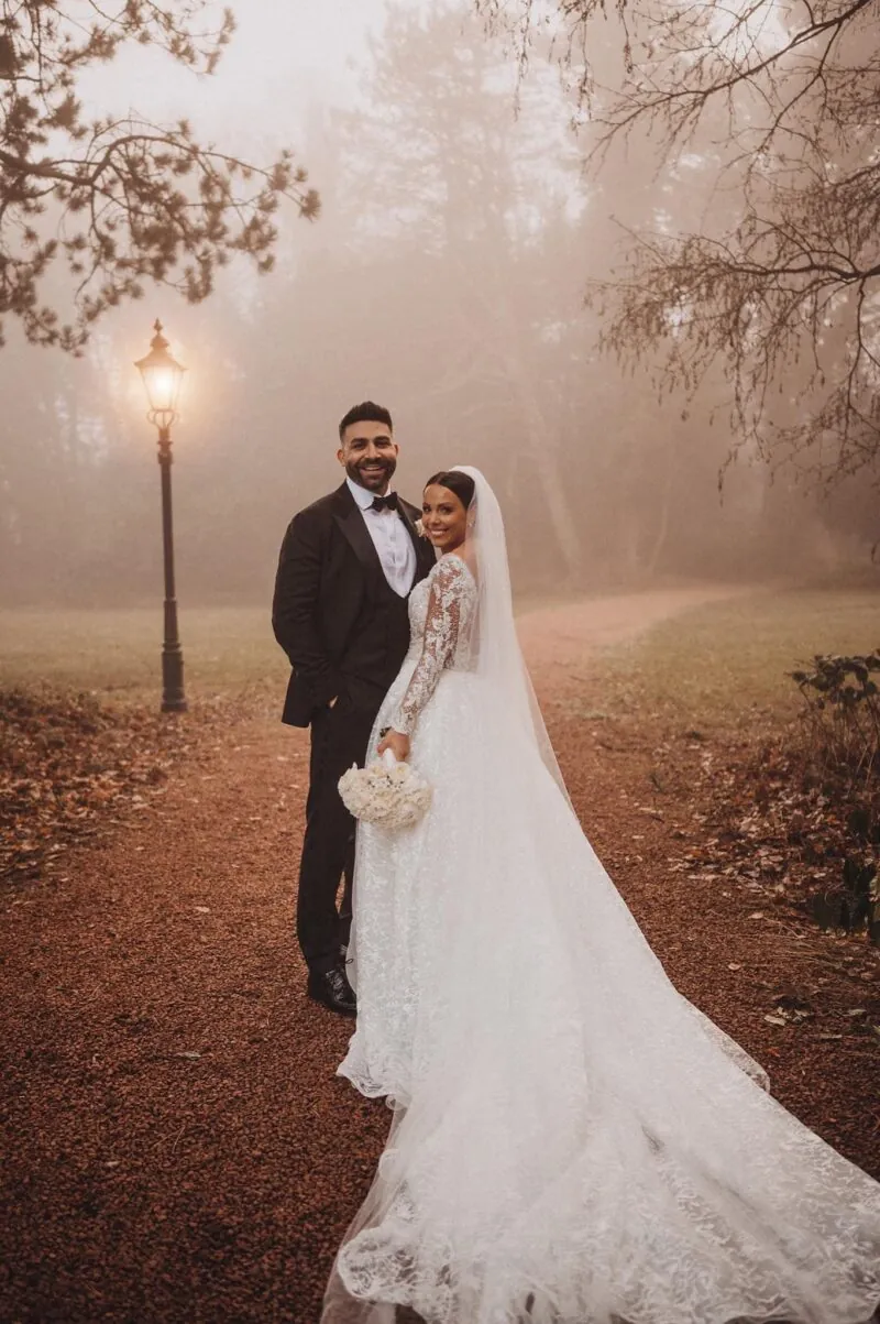 Bride and groom smiling during a misty walk through the autumnal grounds of Abbey House Hotel